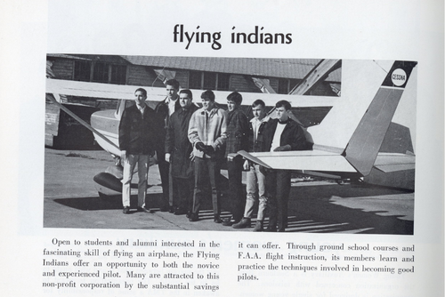 Students pose for a photo at the airport next to a large plane.