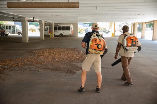 Facilities Managament workers blowing leaves to get them in a pile