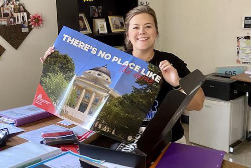 A teacher poses with a SEMO poster
