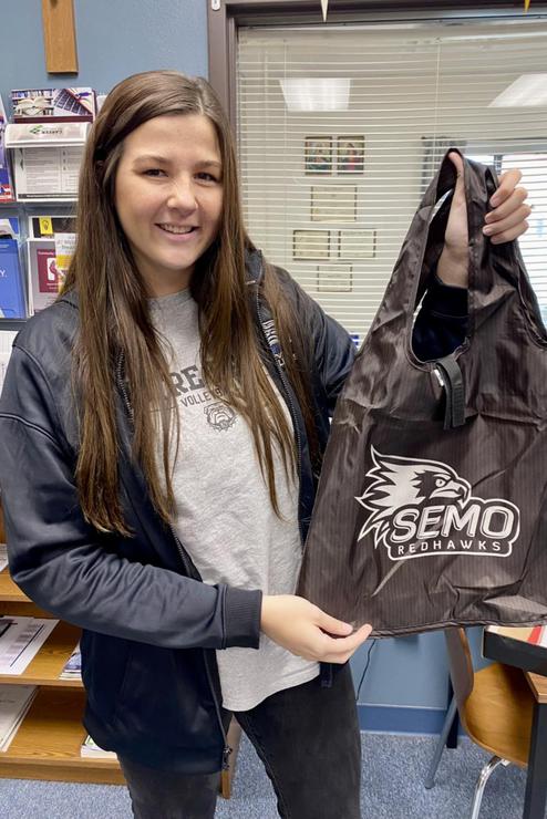 A teacher poses with a tote bag