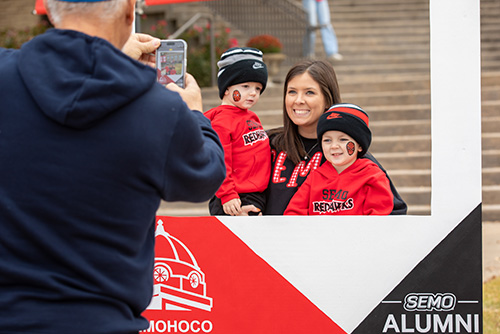 Mom with two kids taking their picture at the photo booth