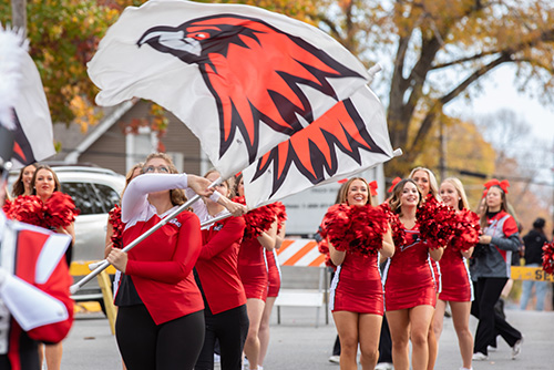 Marching Band Flag girls waving the Redhawks Flag and the sundancers behind them