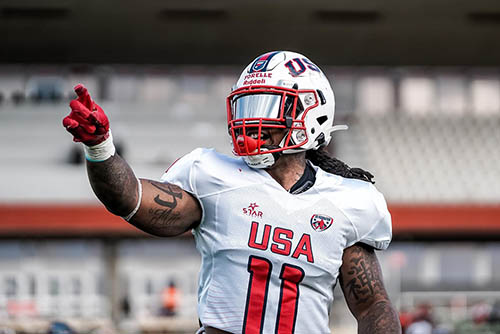 lennies wearing his football uniform and helmet, pointing and talking