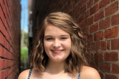 Hannah Jones smiles while standing between brick walls.