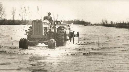 Man on a tractor in flooded farmland.