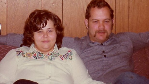 In an old photo, Ron and Jan sit on a couch smiling for the camera.