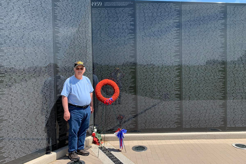 Ron stands in front of a memorial to Vietnam soldiers.