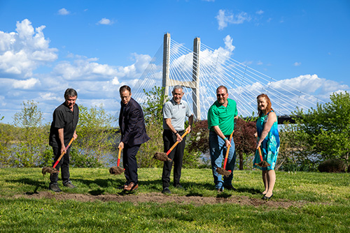 Group of 5 people holding sholves digging into the ground for the groundbreaking