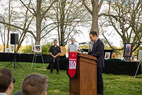 CEO of Mid-America speaking at the podium with SEMO president and the artist listening to him