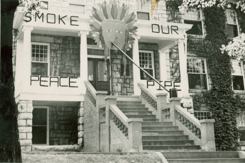 A large illustration of a native american hangs above a dorm next to the words Smoke Our Peace Pipe.