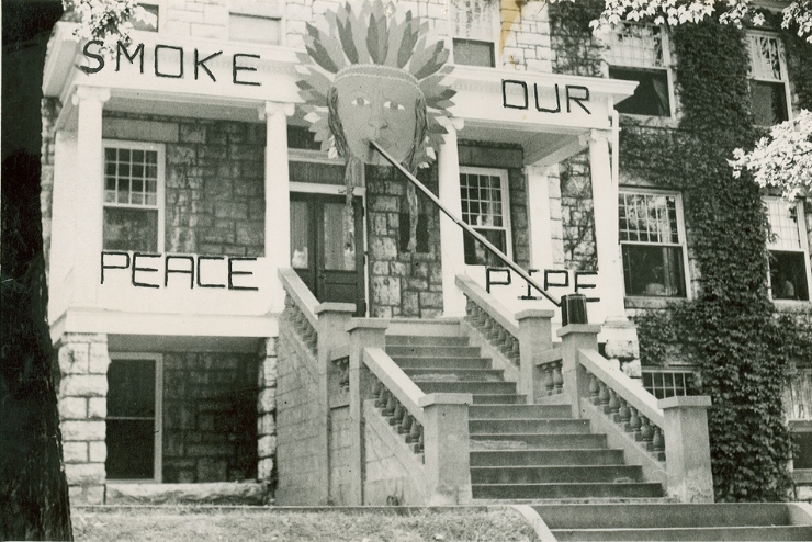 A large illustration of a native american hangs above a dorm next to the words Smoke Our Peace Pipe.