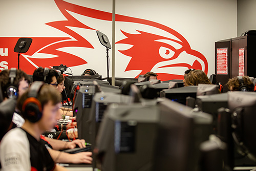 The SEMO Redhawks logo sits above students playing esports