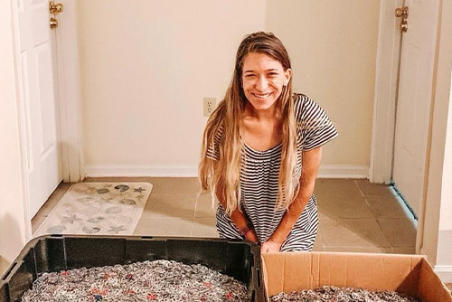 A girl smiles next to boxes