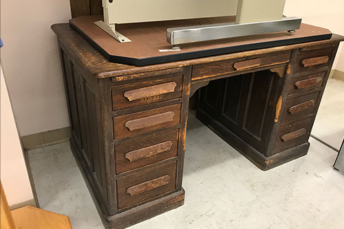 A desk sits in a hallway with stuff on top