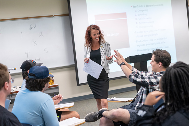 Professor speaking with a small groups of students in a business classroom