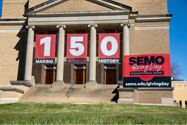 Wehking Alumni Center on a sunny day with a sign for Giving Day on the front lawn.
