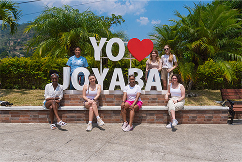 SEMO students sit together in front of a sign that says I love Joyaba