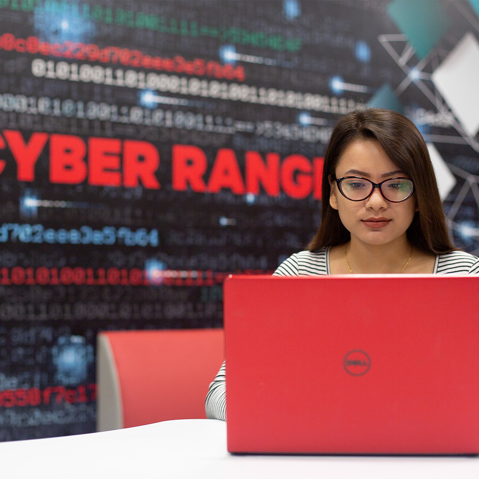 A girl sits on her laptop in front of the cyber Range