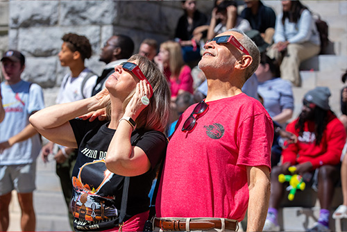 President, Dr. Vargas, and his wife, Pam Vargas, looking up at the eclipse with their glasses on.