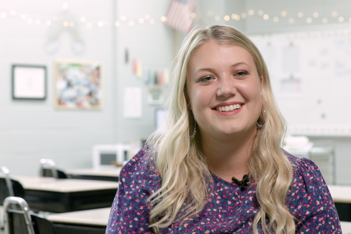 Kamila Allen smiles while sitting in her classroom.