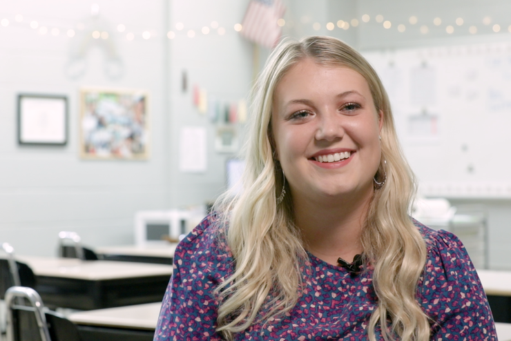 Kamila Allen smiles while sitting in her classroom.