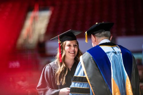 A student walks the stage at graduation to receive her diploma