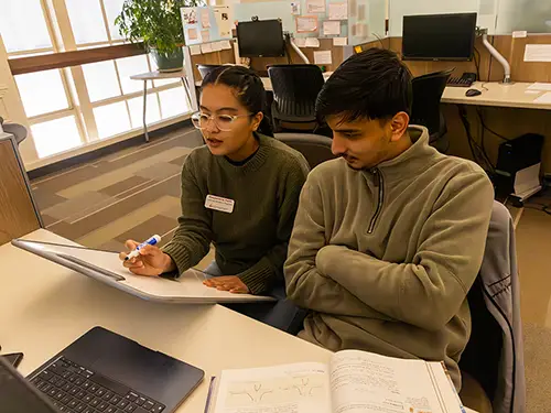 a tutor in the academic support labs helps walk another student through an assignment