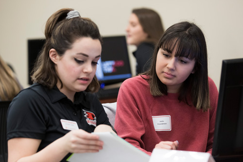 A student looks over documents while receiving advice from a staff member.