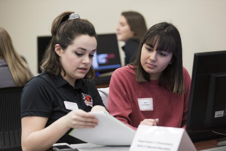 A student looks over documents while receiving advice from a staff member. 