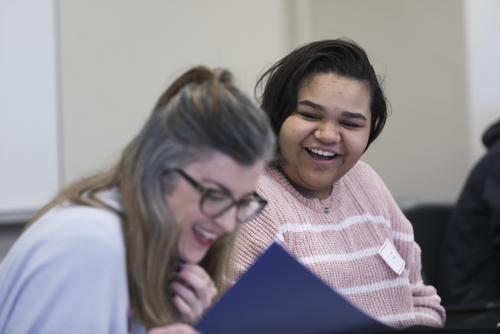 A student smiles while meeting a staff member for advisement.