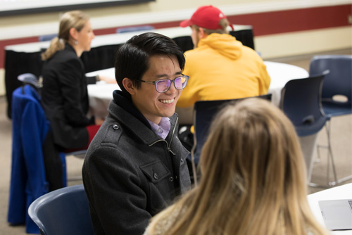 A student smiles while meeting with a faculty member at a First Step event.