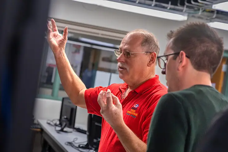 A Semo faculty member gestures while speaking with a CISCO representative.