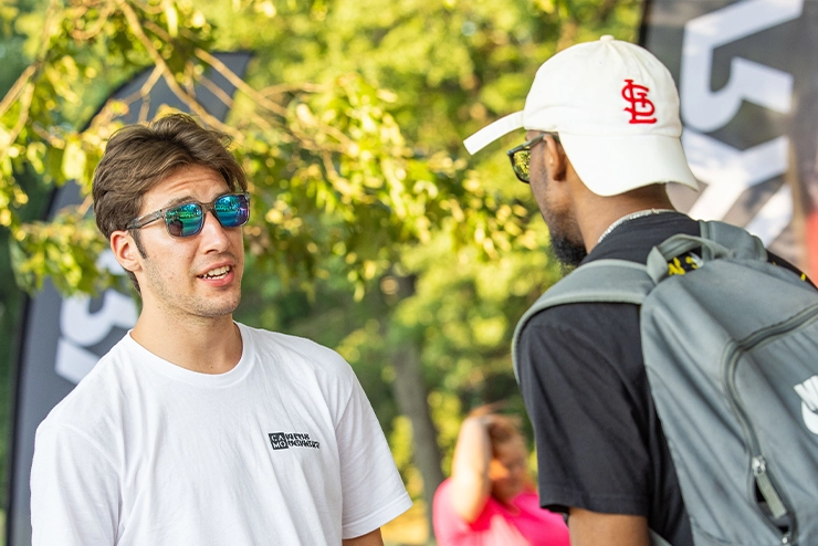 Two students at SEMO talking outside at a booth for involvement in a campus club for supportnet