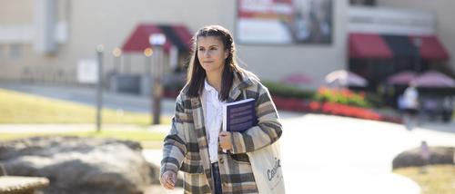 A student carries a book across campus. 