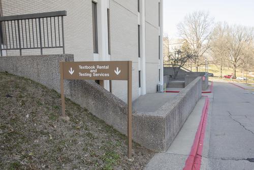 A sign points toward Textbook Rental and Testing Services in the Kent Library basement. 