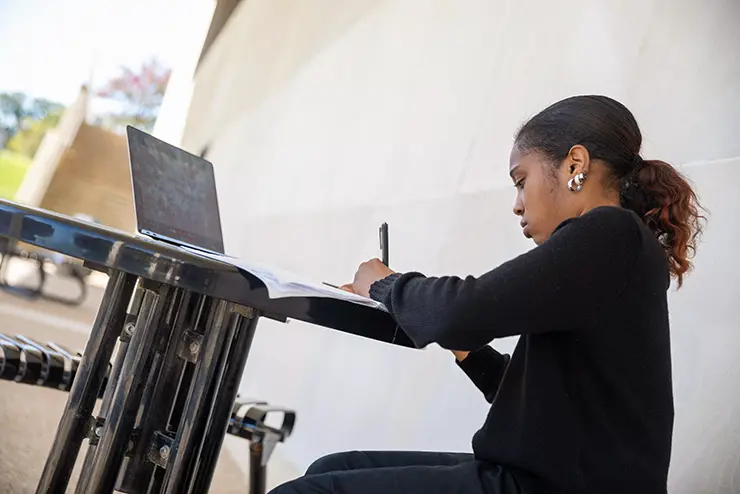 a SEMO student sits outside at a table with her laptop and works