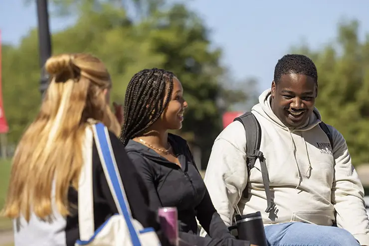 a group of SEMO students sit together outside, talking and laughing