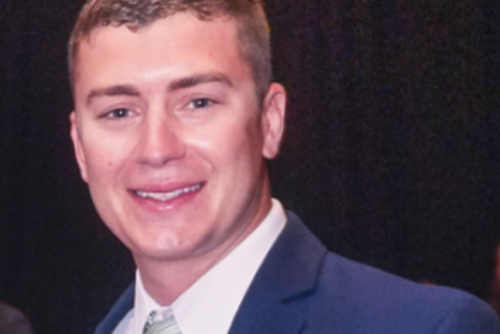 Andy Baker smiling in a suit and tie.