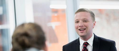 A MBA graduate student smiles while giving a presentation.