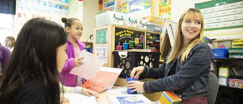 An education student smiles while working with children at a local school.