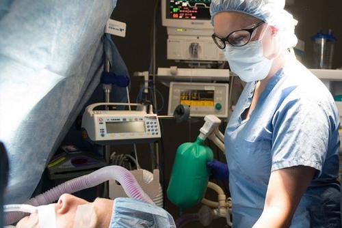 Kaitlyn Brown in scrubs next to an individual prepped for surgery being put under.