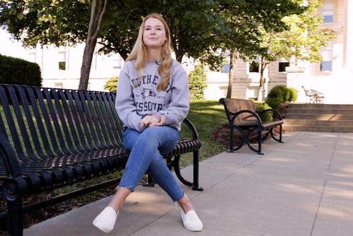 Erin Moore sitting outside on a bench in front of Academic Hall.