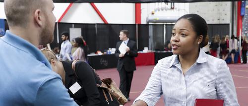 A student shakes hands with an industry professional at a healthcare career expo.