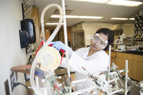A chemistry student wears eye protection while working in a research lab.
