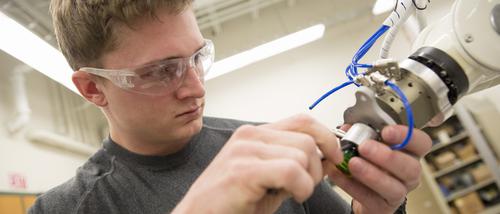 A student works with a piece of machinery in a technology lab.