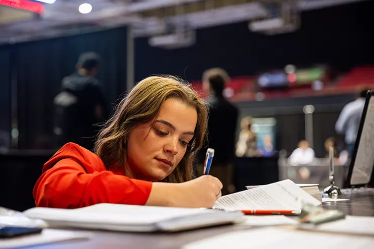 a student works on a piece of paper at a table