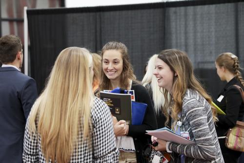 Students share a laugh while mingling at a healthcare career expo.
