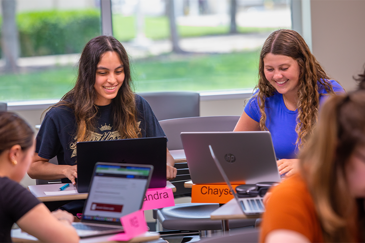 Group of SEMO students smiling as they work on their laptops