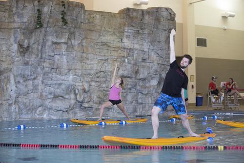 Students participate in a paddleboard yoga class at the Aquatic Center in the Recreation Center.