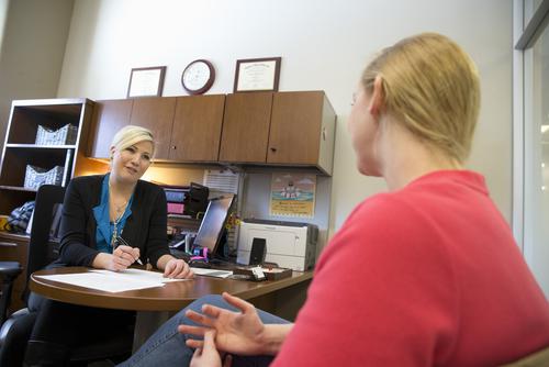 A career services staffer speaks with a student while reviewing a resume. 